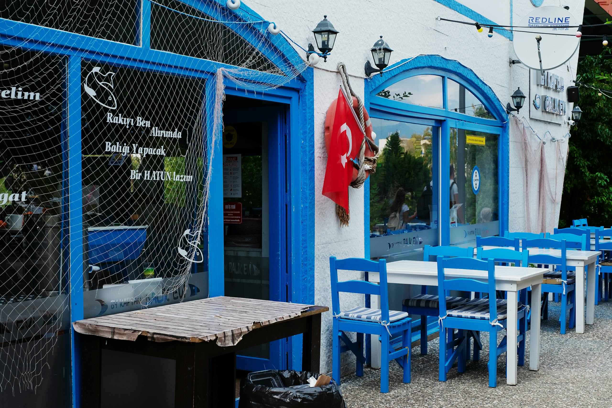 Exterior view of a Turkish restaurant with blue decor and flag, inviting outdoor dining ambiance.