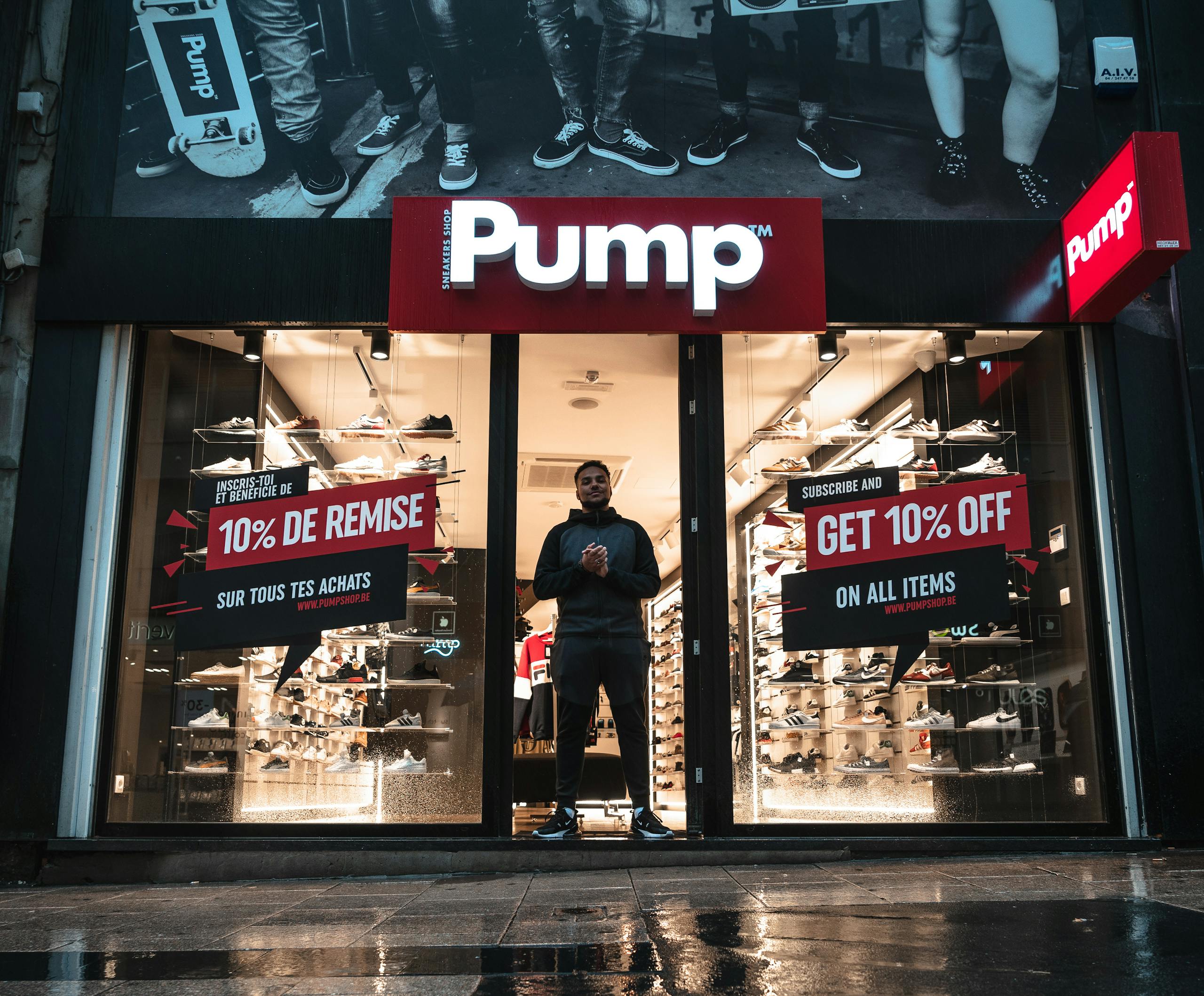 Illuminated shoe store Pump in Brussels with sale signs and reflections at night.