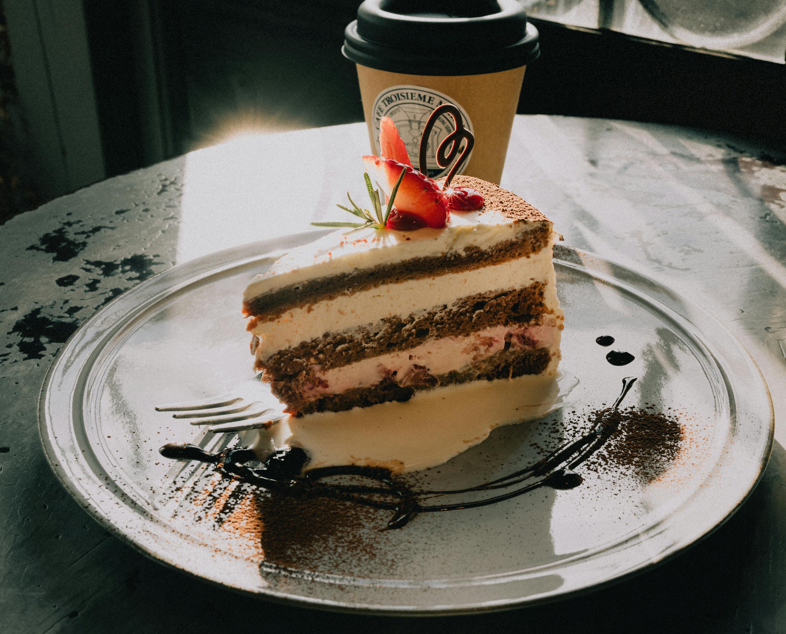 Delicious slice of gourmet cake with coffee in a sunlit setting, highlighting a cozy café atmosphere.